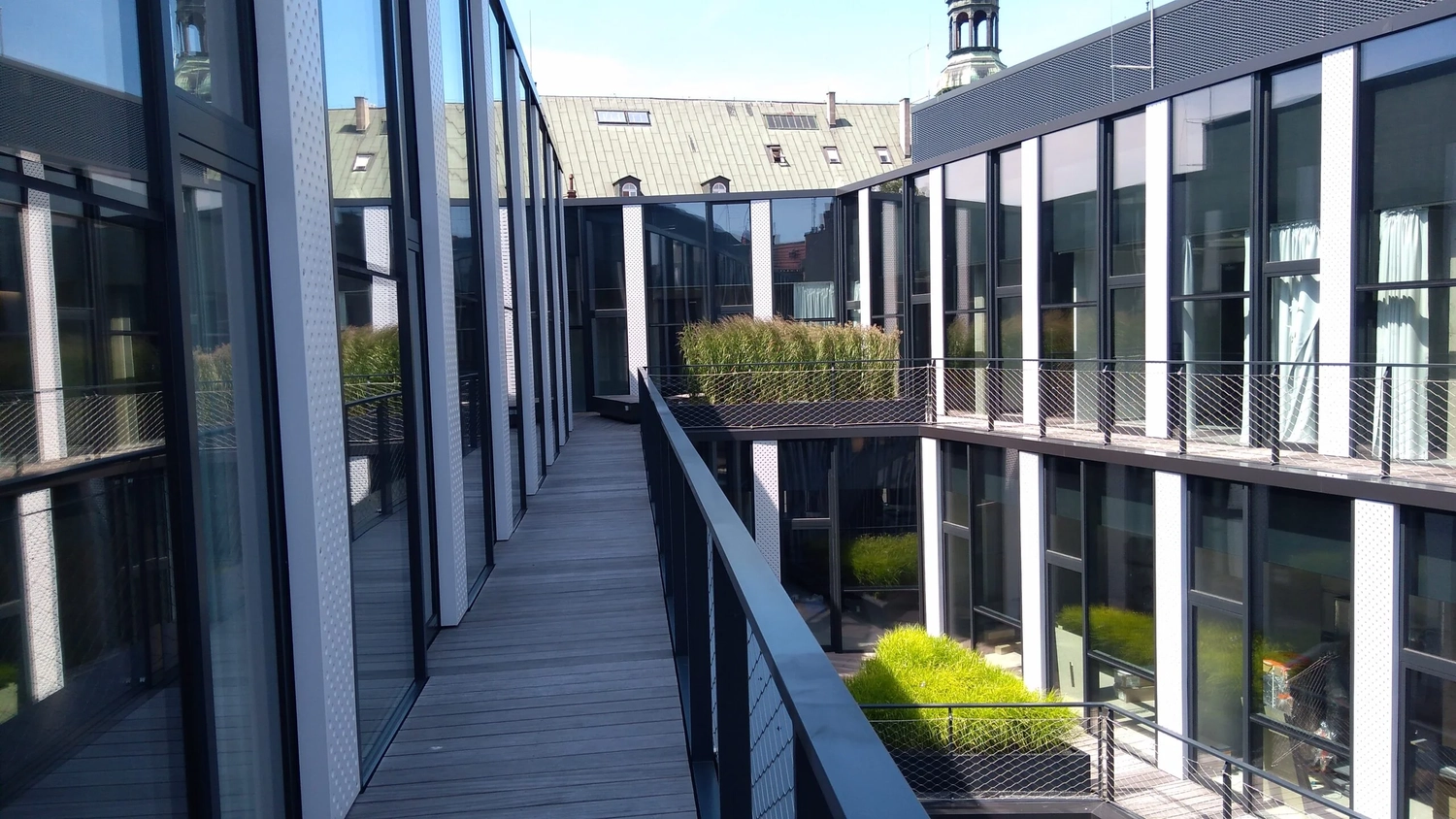 Cybulski Trockenbau - Bau und Fensterbauer - Modernes Bürogebäude mit einem offenen Holzsteg, Glasfassaden und Aluminiumfenstern, die einen Innenhof umschließen.